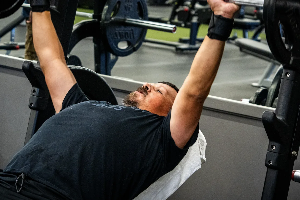 Member pressing on a plate loaded chest press machine with weight plates on each side at The Training Room