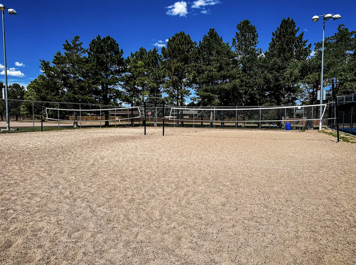 Sand volleyball court with net, rope boundary lines and light poles under a clear sky at The Center