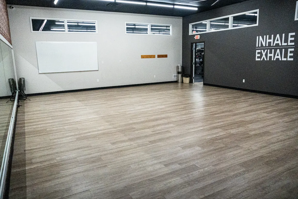 Open group fitness studio with hardwood floor, mirrors and Inhale Exhale wall graphic at The Training Room