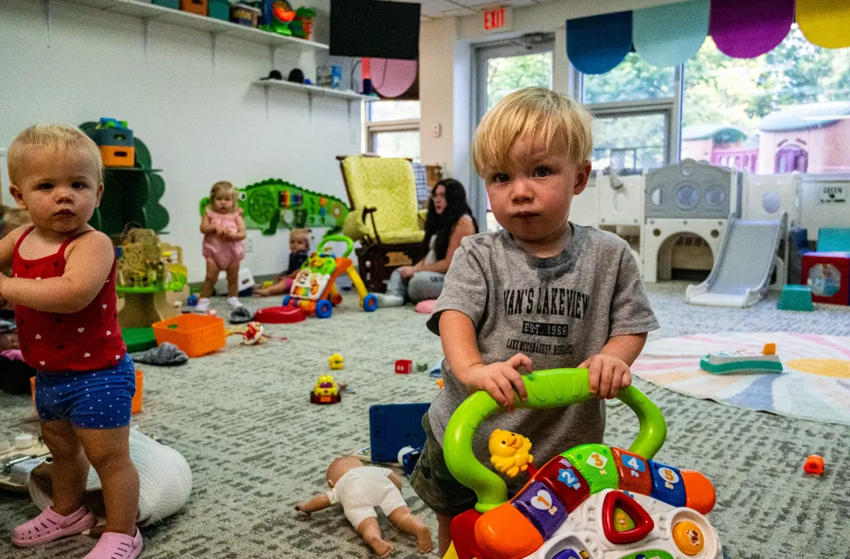 Toddlers playing with push toys on the carpet in the Kids Korner Mobile Room
