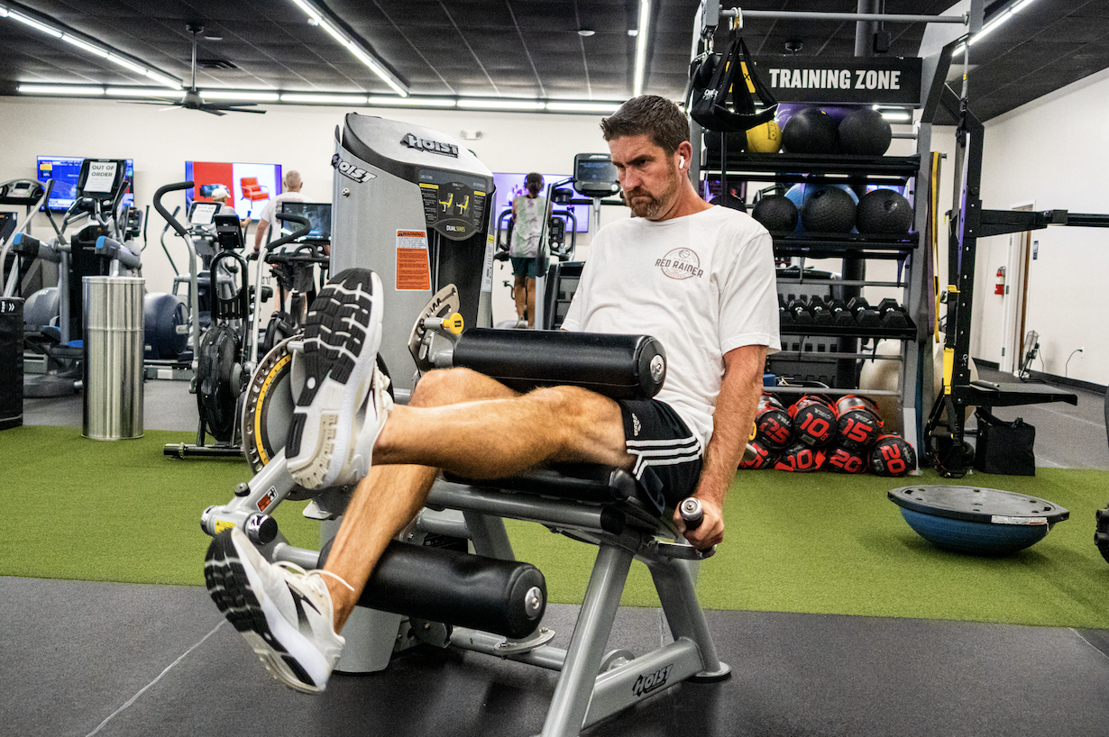 Member using a selectorized Hoist leg extension machine on the turf training floor at The Training Room
