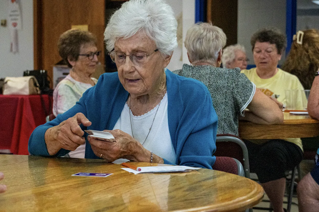 Senior members playing cards together at a table at The Center