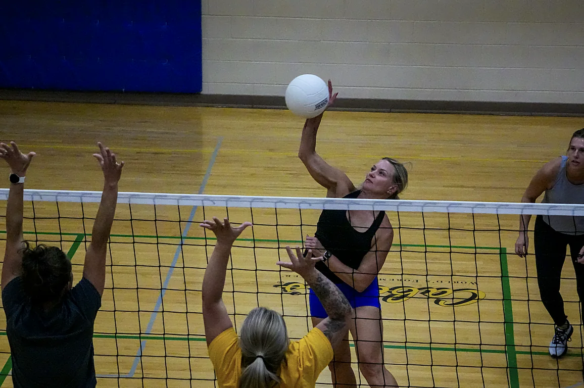 Adult volleyball player reaching above the net to return the ball at The Center