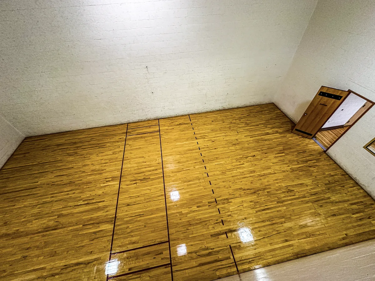 Indoor racquetball court with glossy hardwood floor and red court lines at The Center