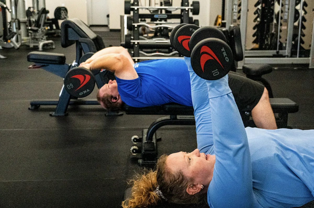 Members training with dumbbells on weight benches at The Training Room