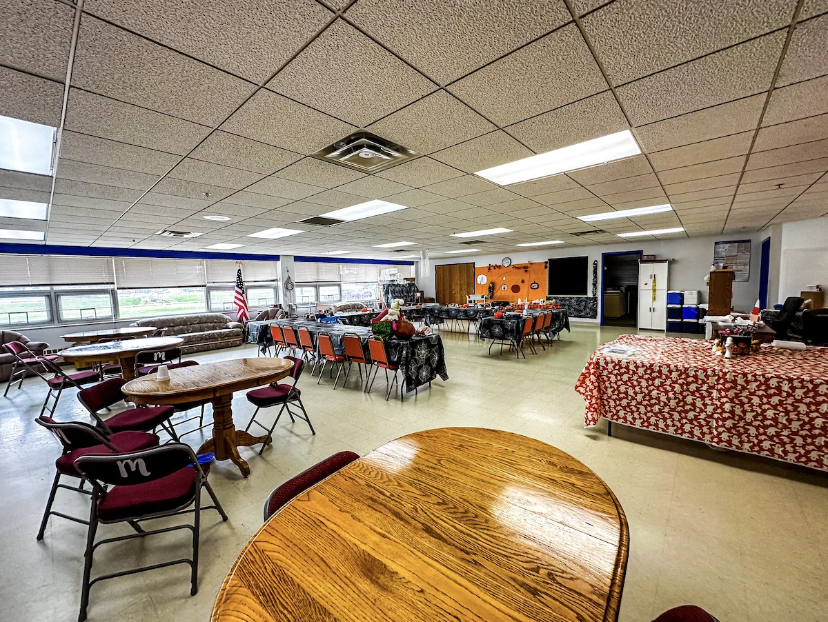 The Center's Meeting Room with round and rectangular tables, chairs and windows along the wall