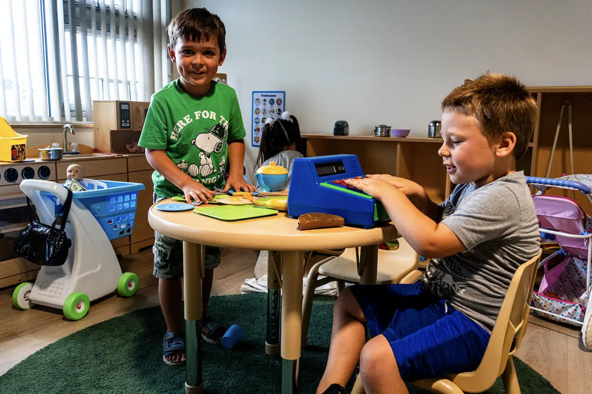 Two preschoolers playing together in the classroom play kitchen