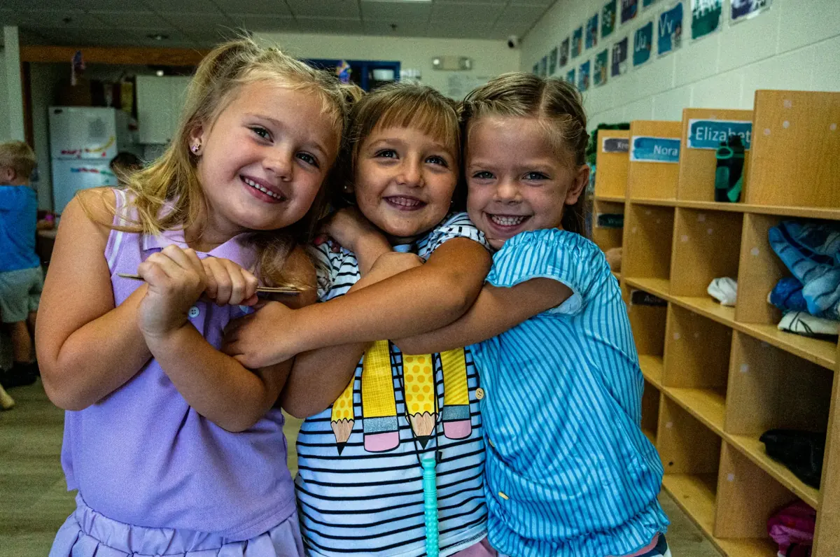 Three Playschool friends hugging and smiling in their Kids Korner classroom