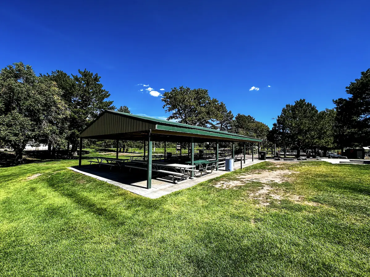 Green-roofed open-air picnic shelter with wooden picnic tables at Legion Park